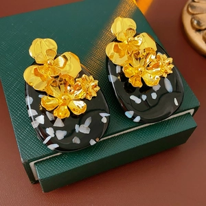 Close-up of vintage metal flower earrings with white stones on a green gift box
