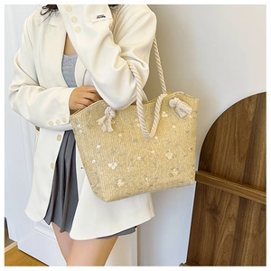 Détail du sac cabas en paille beige avec broderie florale et anses en corde épaisse