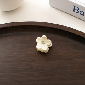Gros plan d'une mini pince à cheveux fleur blanche posée sur un plateau en bois vintage