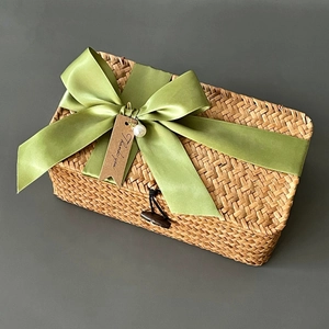 Detail of rectangular woven seagrass gift box with a green ribbon and pearl charm