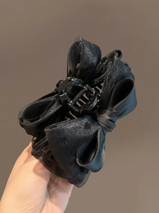 Close-up of black organza bow hair claw clip with subtle glitter details
