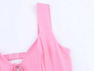 Detail of pink dress featuring wide shoulder straps, lace-up neckline and pleated texture