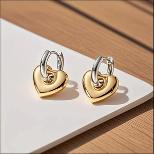 Macro detail of two-tone heart pendant earrings in gold and silver finish