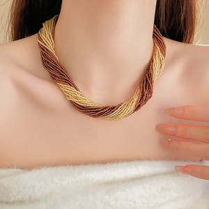 Close-up of layered French vintage necklace with twisted gold and brown seed beads