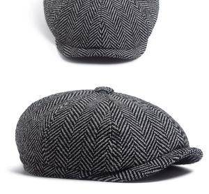 Close-up of black and white herringbone fabric texture and top button on newsboy cap