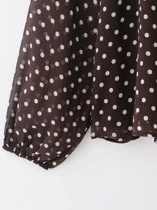 Dettaglio camicia a pois marrone scuro con polsini elastici a balze e tessuto semitrasparente