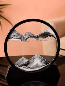 Detail of round sand art picture with orange black white sand and sleek black frame