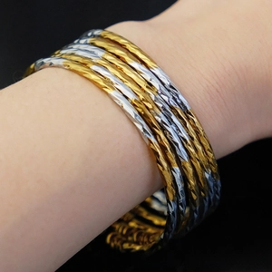 Close-up of 3mm gold and silver faceted bangles showing textured diamond-cut finish