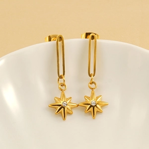 Elegant gold 18K plated eight-point star drop earrings hanging on a white ceramic vase