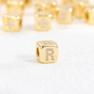 Macro shot of 18k gold plated cube bead with sparkling cubic zirconia letter R detail