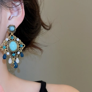 Close-up of bohemian vintage gold earrings with turquoise stones and droplet beads