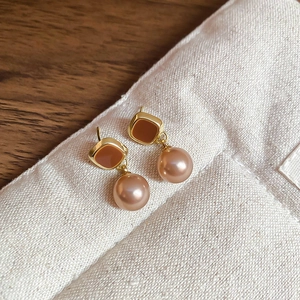 Close-up of vintage square stud earrings with brown enamel and champagne pearls