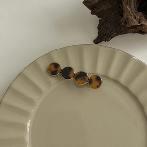 Detail of tortoise shell acetate claw clip on a ceramic tray with gold metal accents