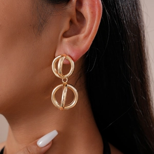 Close-up of elegant gold hollow geometric earrings worn by a model with metallic finish