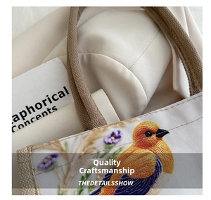 Nahaufnahme der Vogel- und Blumenstickerei auf der beigefarbenen Canvas-Einkaufstasche