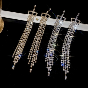 Macro shot of silver needle tassel earrings with crown motif and sparkling zircons
