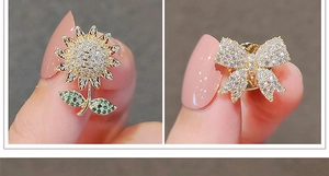 Détail macro de broches dorées en forme de tournesol et de nœud serties de zircones