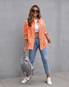 Detail der orangefarbenen Denim-Jacke mit ausgefransten Kanten und lässigem Revers-Stil