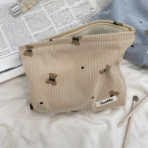 Macro view of beige corduroy cosmetic bag featuring cute bear pattern and heart print texture