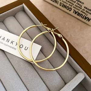 Detailed view of large gold hoop earrings on a velvet display tray with elegant decor
