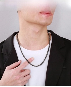 Detail of men's vintage steel Franco chain worn over a white T-shirt and black suit