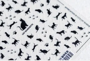 Close-up of 5D nail art stickers featuring black cat silhouettes and paw prints
