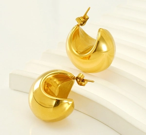 Dettaglio macro di orecchini a C placcati oro 18K lucidi su supporto espositivo bianco