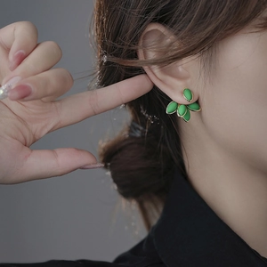 Eleganti orecchini a foglia verde con bordo dorato indossati da una modella in primo piano