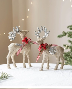 Detail of champagne gold glitter reindeer statues with red berries and festive ribbons
