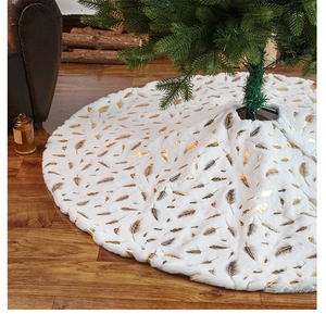 Detail of plush white Christmas tree skirt with gold feather print on wooden floor