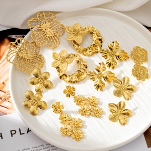 Macro shot of assorted gold flower earrings with metallic textures in a ceramic dish