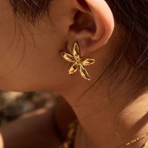 Elegant gold stainless steel flower stud earrings worn on a model with a 3D floral design