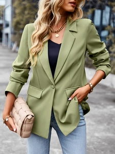 Close-up of a green short-sleeved blazer featuring a single-breasted button and flap pockets