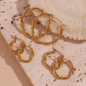 Three pairs of twisted gold hoop earrings in small, medium, and large sizes on stone background