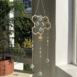 Honeycomb suncatcher with pink crystals and golden bees hanging by a window