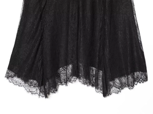 Detailed close-up of black lace fabric and irregular wavy hemline on a midi skirt