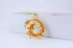 Macro view of golden dragon keychain with orange scale textures and red gemstone details