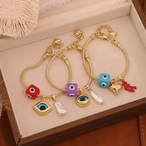 Detailed macro view of 18K gold-plated bracelets with evil eye charms and pearls