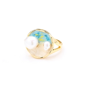 Détail d'une bague dorée en émail bleu et blanc ornée de deux perles naturelles