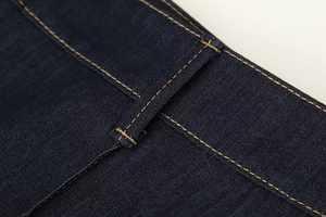 Vue détaillée d'un pantalon en denim indigo avec surpiq surpiqûres orange et passant de ceinture
