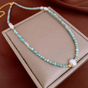 Vue macro d'un collier en amazonite et perles plaqué or sur un écrin à bijoux