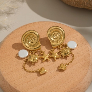Golden sun and starfish tassel earrings with white pearls on a rustic wood base