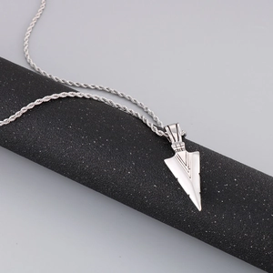 Detailed close-up of a silver stainless steel arrow pendant necklace on a black stand