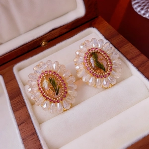 Detailed close-up of vintage crystal floral earrings in a premium wooden jewelry box