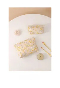 Détail de deux trousses à maquillage en lin beige avec broderie florale et fermeture éclair