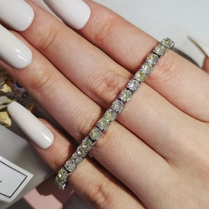 Detail of hip hop tennis bracelet with yellow and white square zircons on female wrist