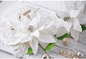 Detail of white artificial poinsettia with silver glitter edges on a wooden tray