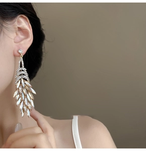 Detail view of luxurious champagne crystal fringe earrings on model with gold plating