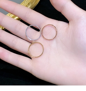 Detailed view of three minimalist faceted stackable rings in silver, gold, and rose gold