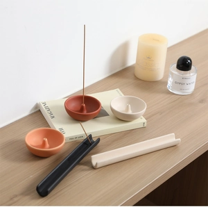 Porta-inciensos cerámicos minimalistas en varios colores sobre una mesa de madera